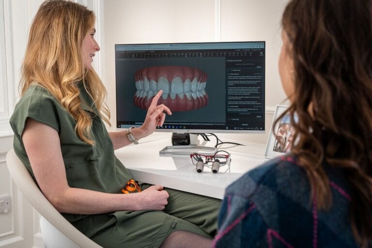 A dentist explains a 3D dental model to a patient during a consultation.